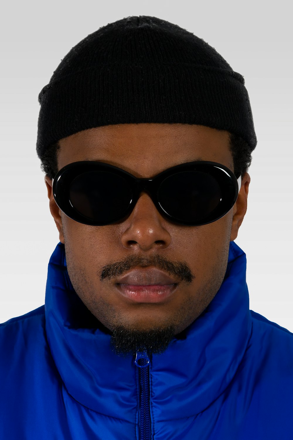 man in blue jacket wearing black knit cap and black sunglasses