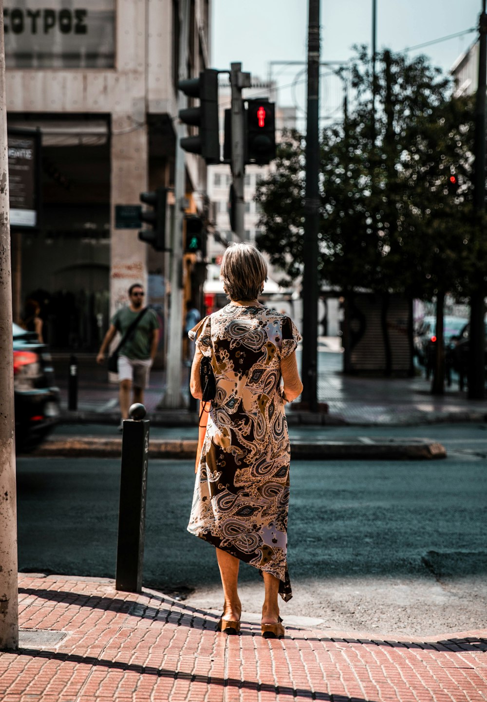 woman in yellow and black floral dress standing on sidewalk during daytime