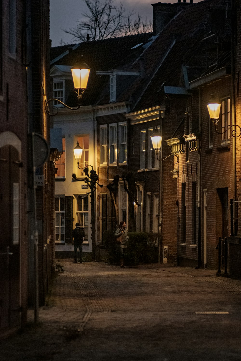 empty street with light posts between buildings during night time
