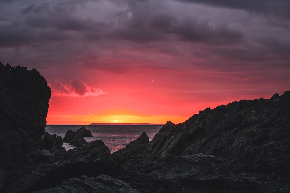 silhouette of mountain near body of water during sunset