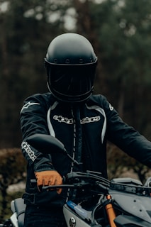 man in black and orange helmet riding black motorcycle