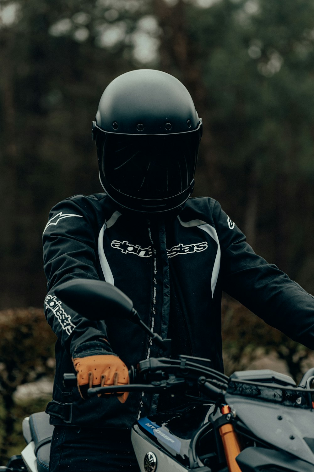 man in black and orange helmet riding black motorcycle