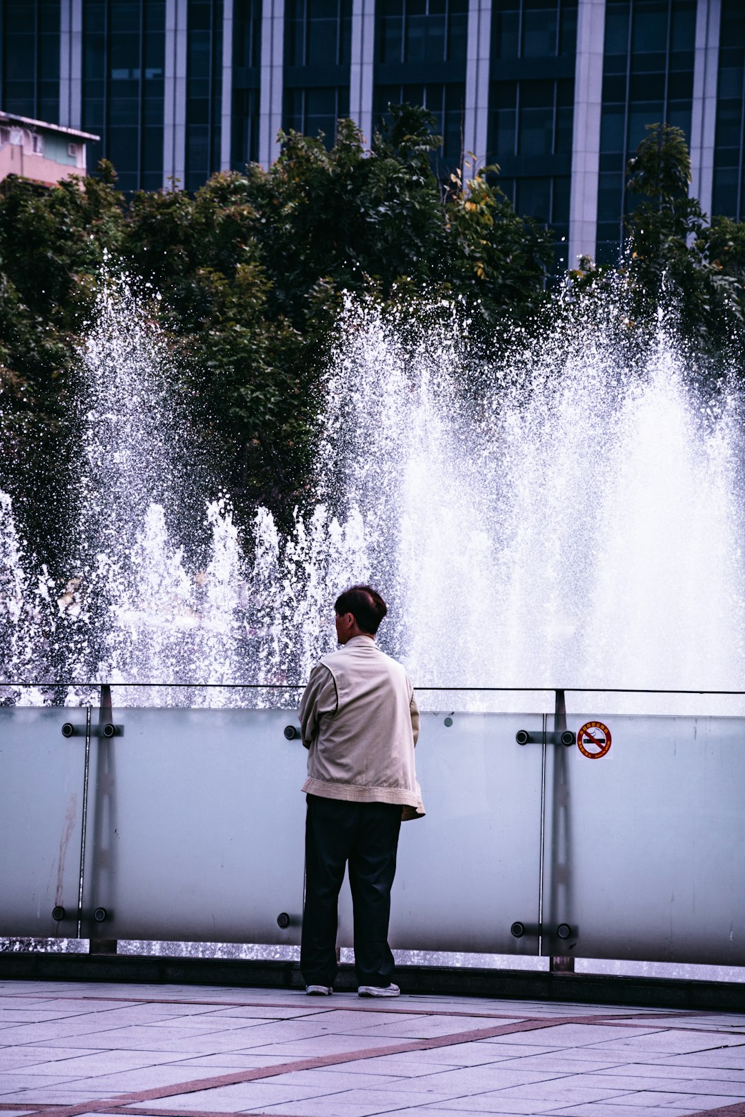 man in white hoodie standing in front of water fountain