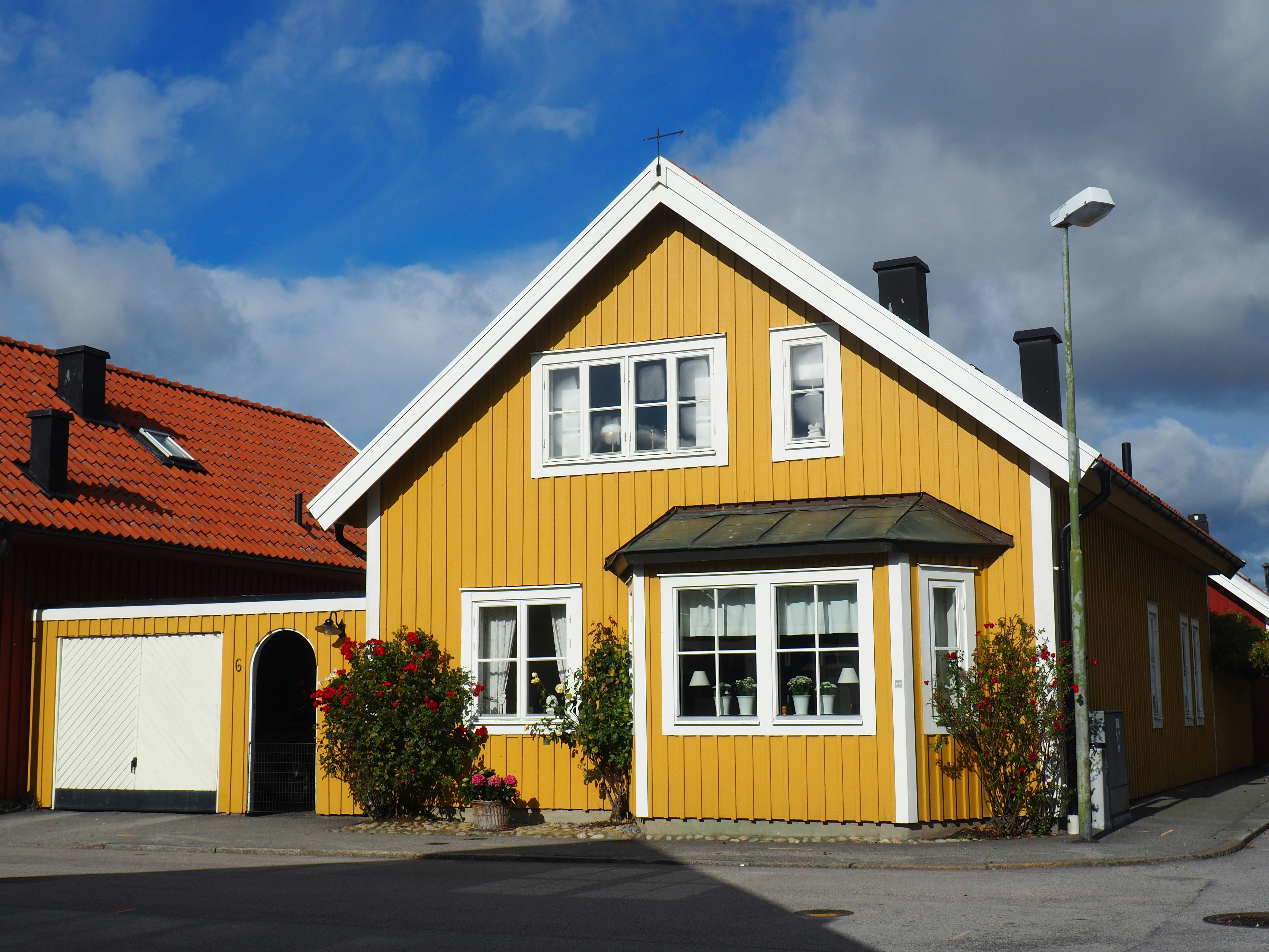brown and white wooden house near green trees under blue sky during daytime