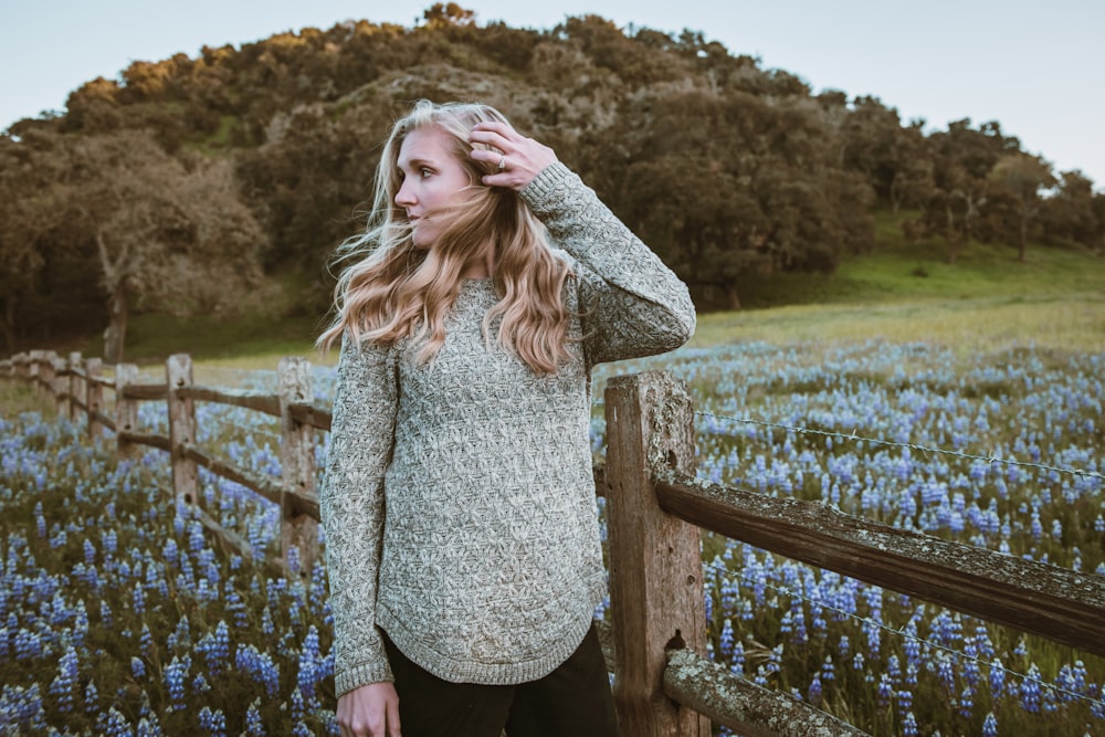 woman in gray sweater standing on green grass field during daytime