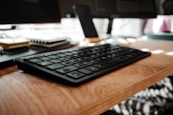 Close-up of hands typing on a keyboard with colorful sticky notes in the background.