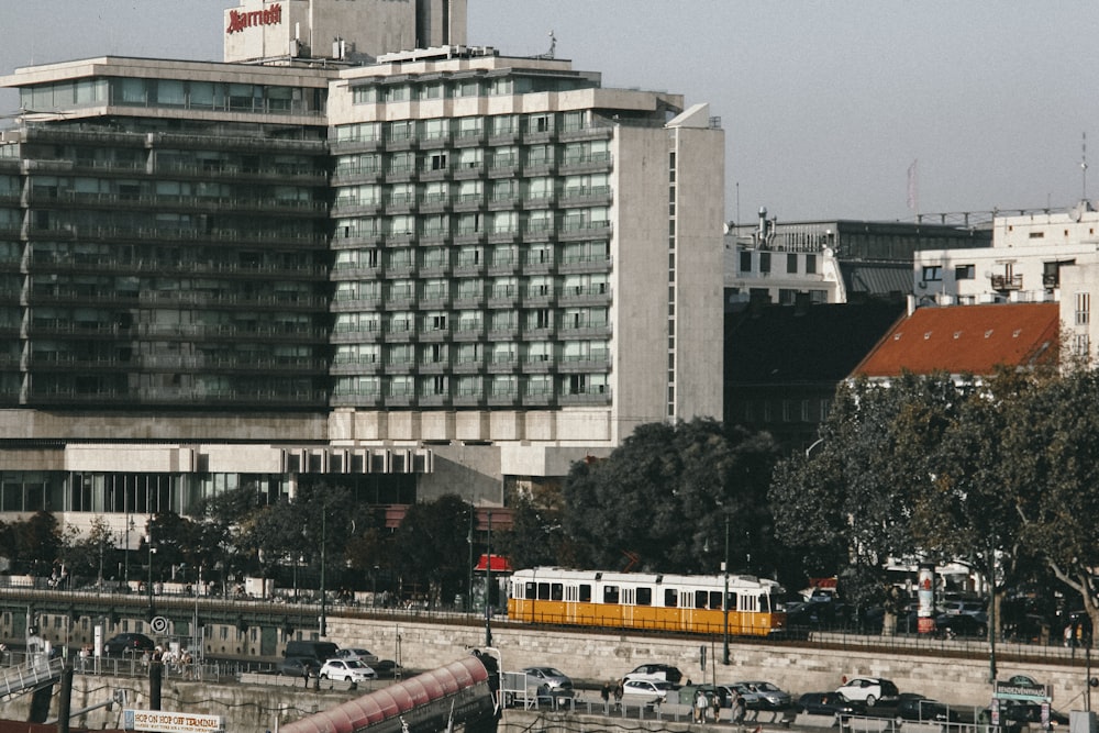 white and yellow bus on road near white concrete building during daytime