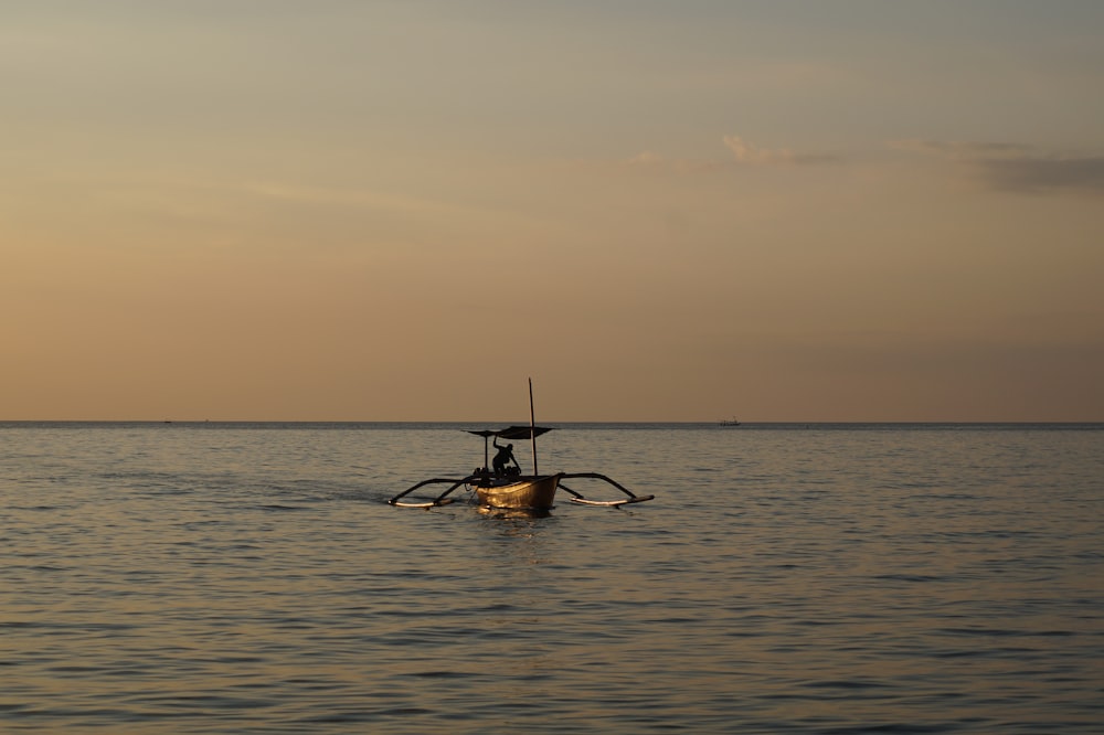 homme équitation sur le bateau sur la mer au coucher du soleil