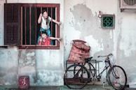 woman in white t-shirt and blue denim jeans standing beside red bicycle