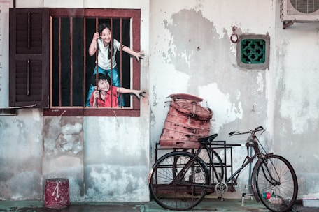 woman in white t-shirt and blue denim jeans standing beside red bicycle