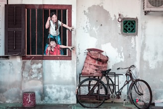 woman in white t-shirt and blue denim jeans standing beside red bicycle