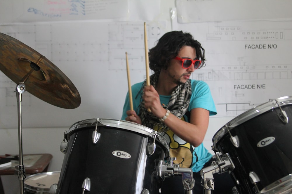 a man playing drums in front of a wall