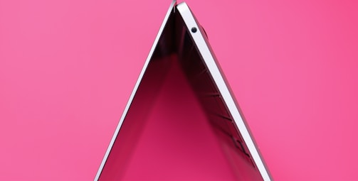 A bright pink-themed simple website homepage on a laptop screen.