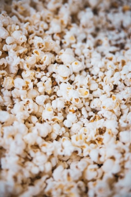 A close-up of freshly popped popcorn, with kernels displaying a variety of shapes and a fluffy texture. The overall appearance is crisp and appetizing.
