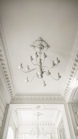 Elegant stucco details framing a stylish chandelier in a dining room setting.