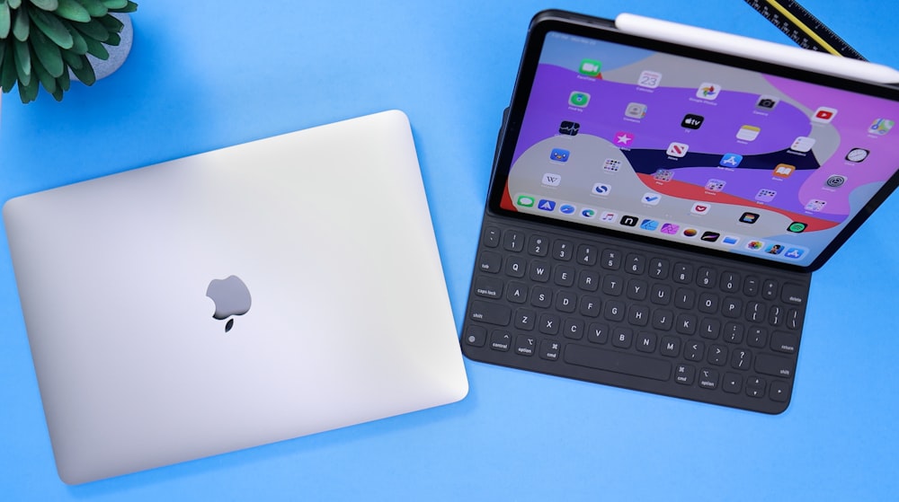 MacBook plateado junto al teclado negro de la tableta