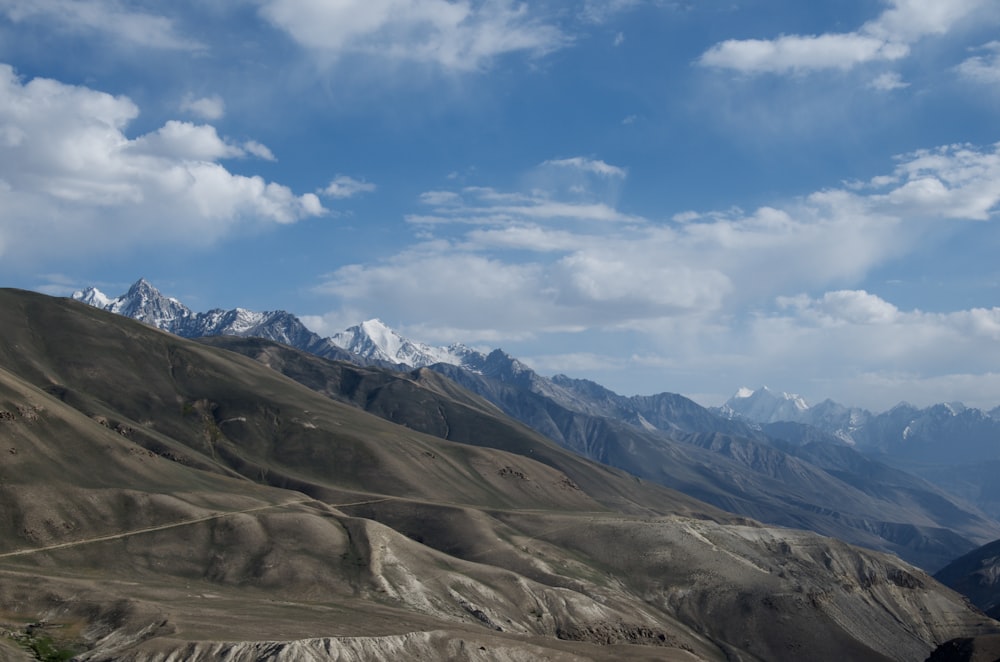 brown and green mountains under blue sky and white clouds during daytime