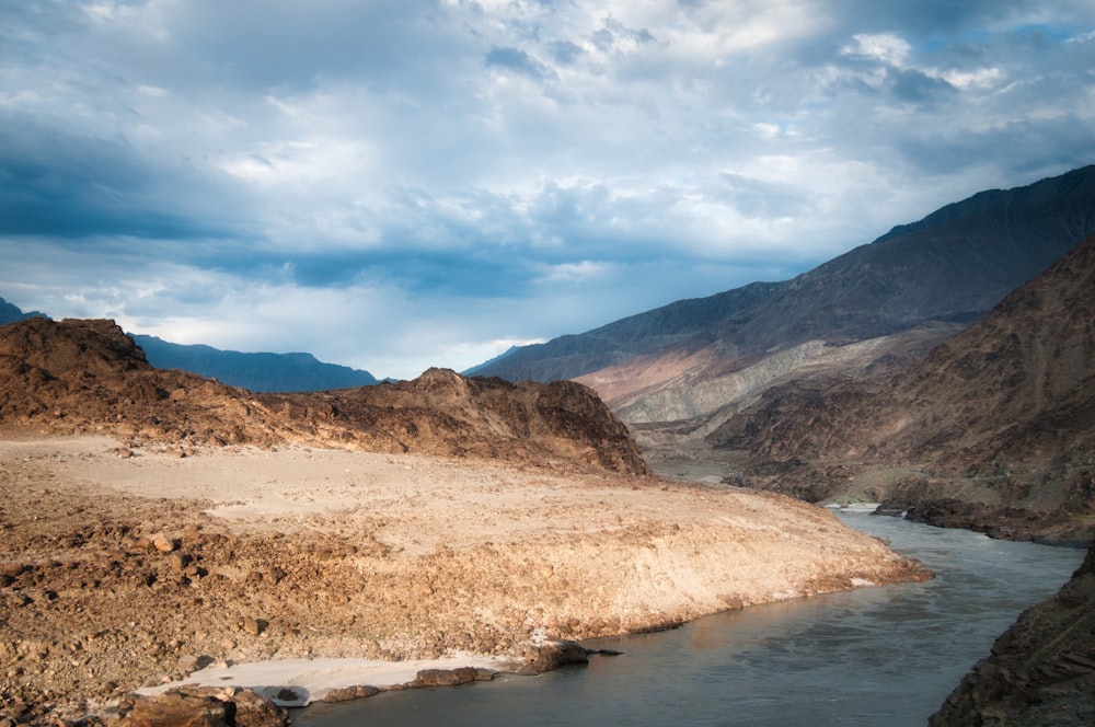 brown mountain near body of water under blue sky during daytime