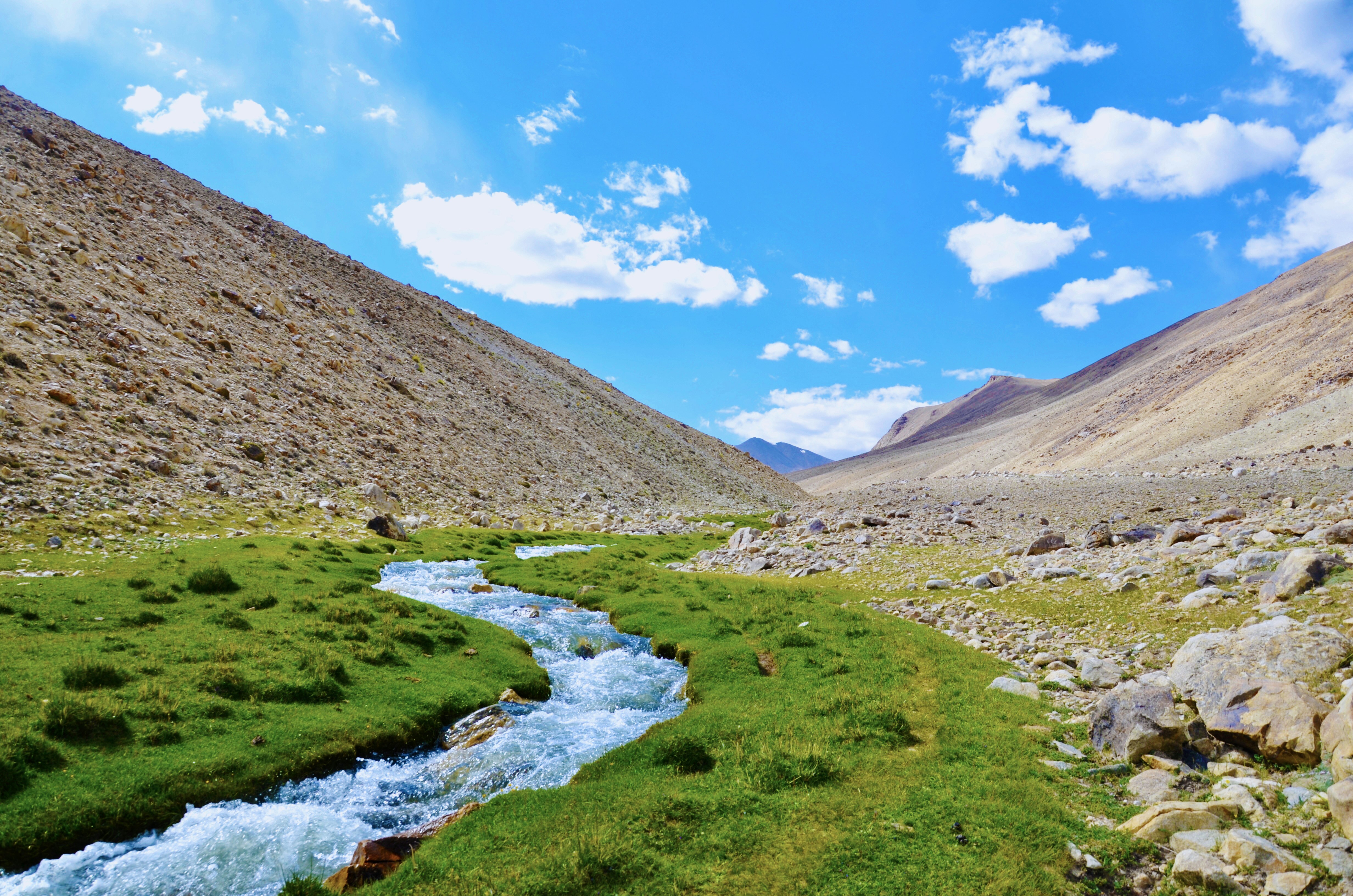 river in between brown mountains under blue sky during daytime