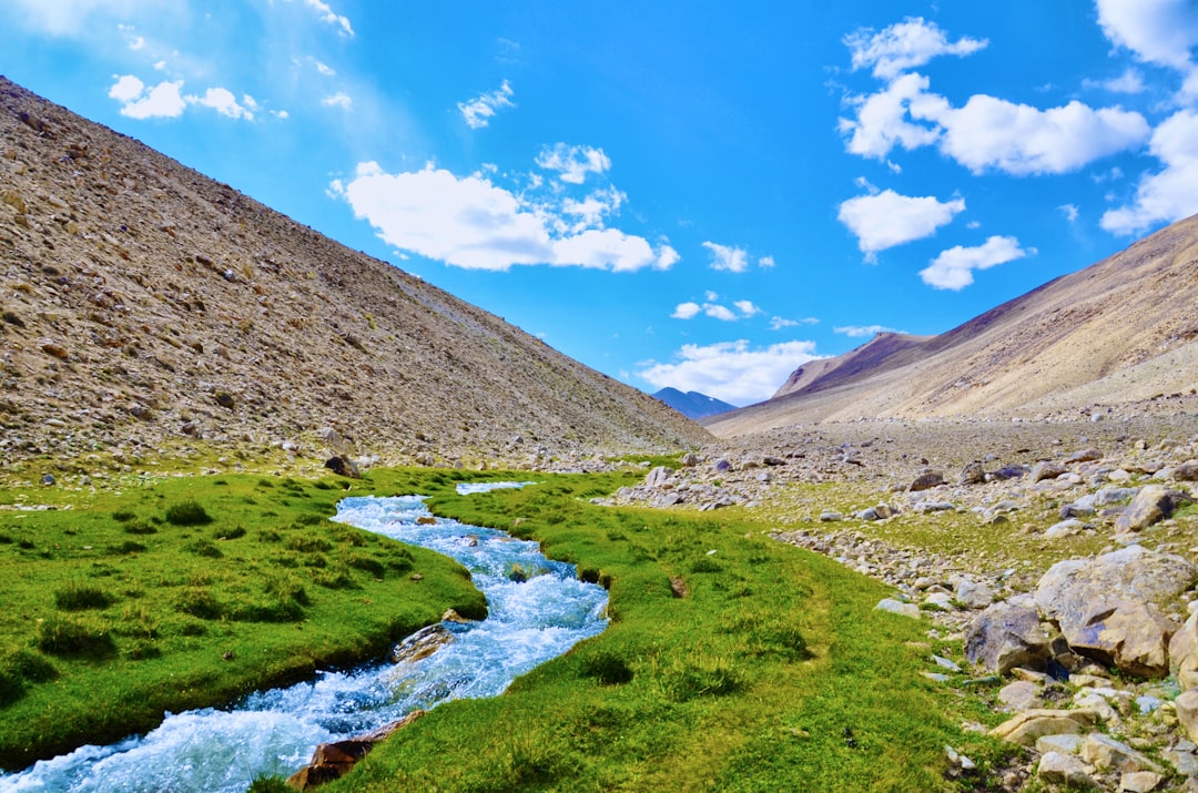 river in between brown mountains under blue sky during daytime