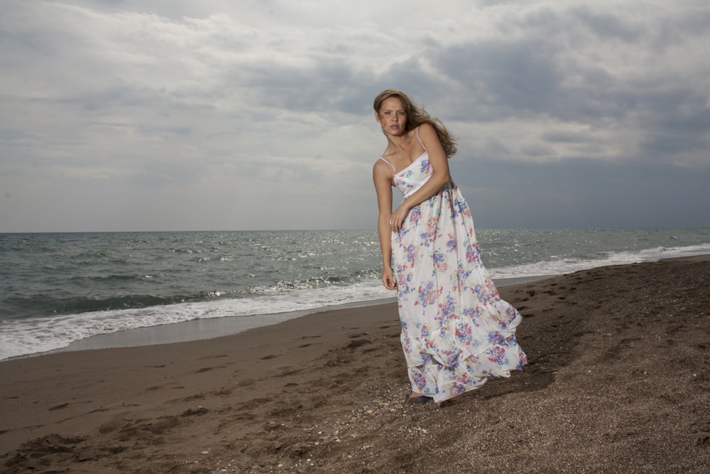 woman in white and pink floral dress standing on beach during daytime