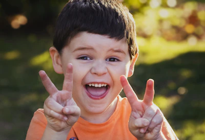 boy in orange crew neck shirt smiling