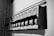 A close-up view of an electrical circuit breaker panel featuring multiple labeled toggle switches. Each switch has labels with details such as voltage and circuit specifications. The panel is monochrome, highlighting the structural design and text.
