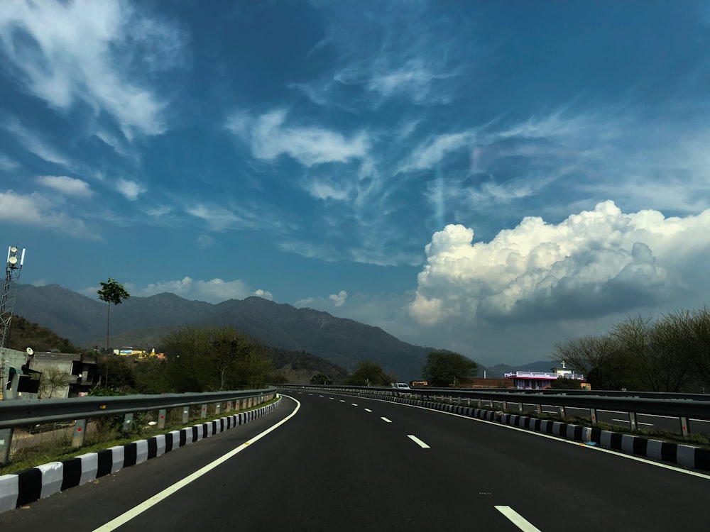Carretera de hormigón gris bajo el cielo azul y las nubes blancas durante el día