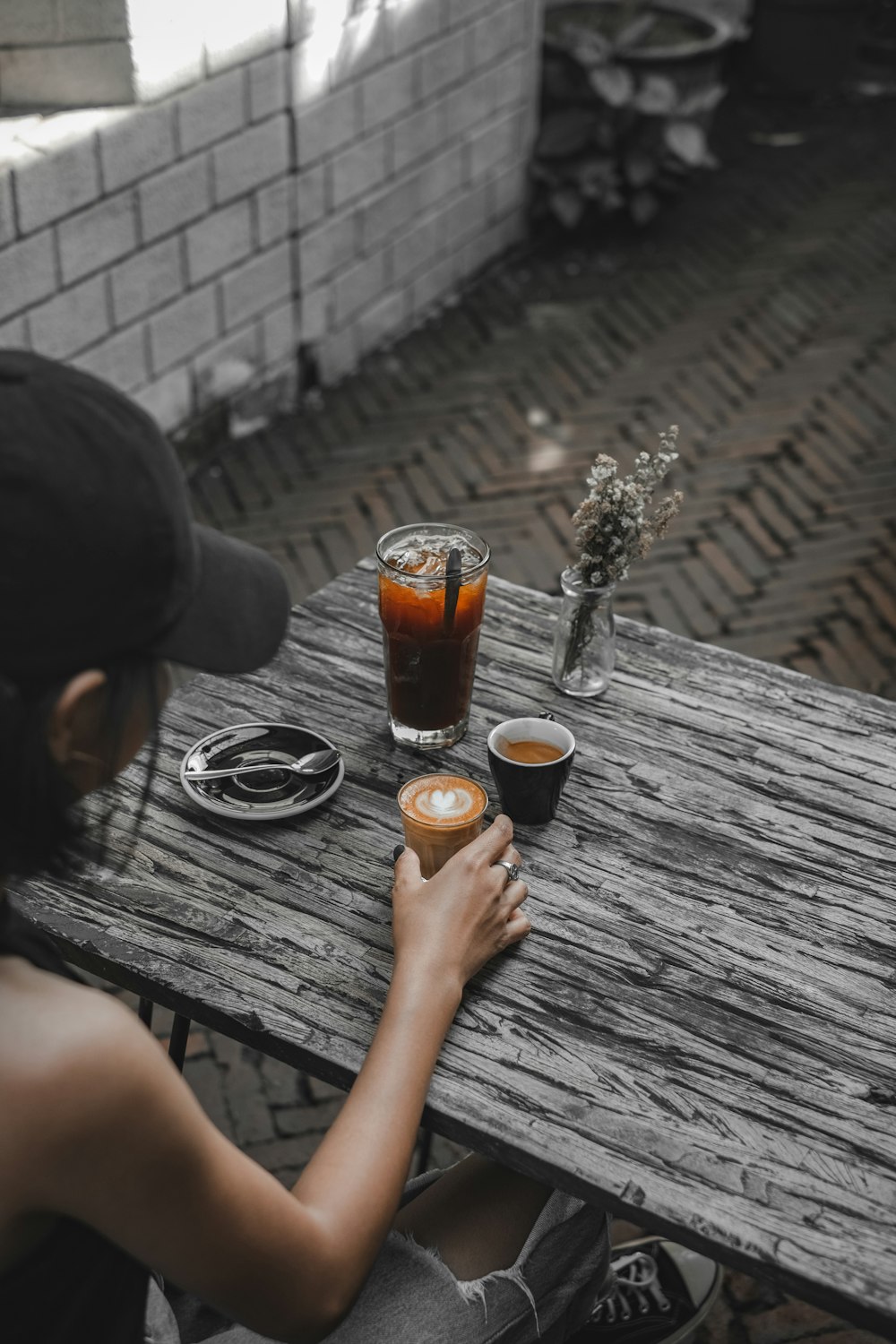 person holding clear drinking glass with brown liquid