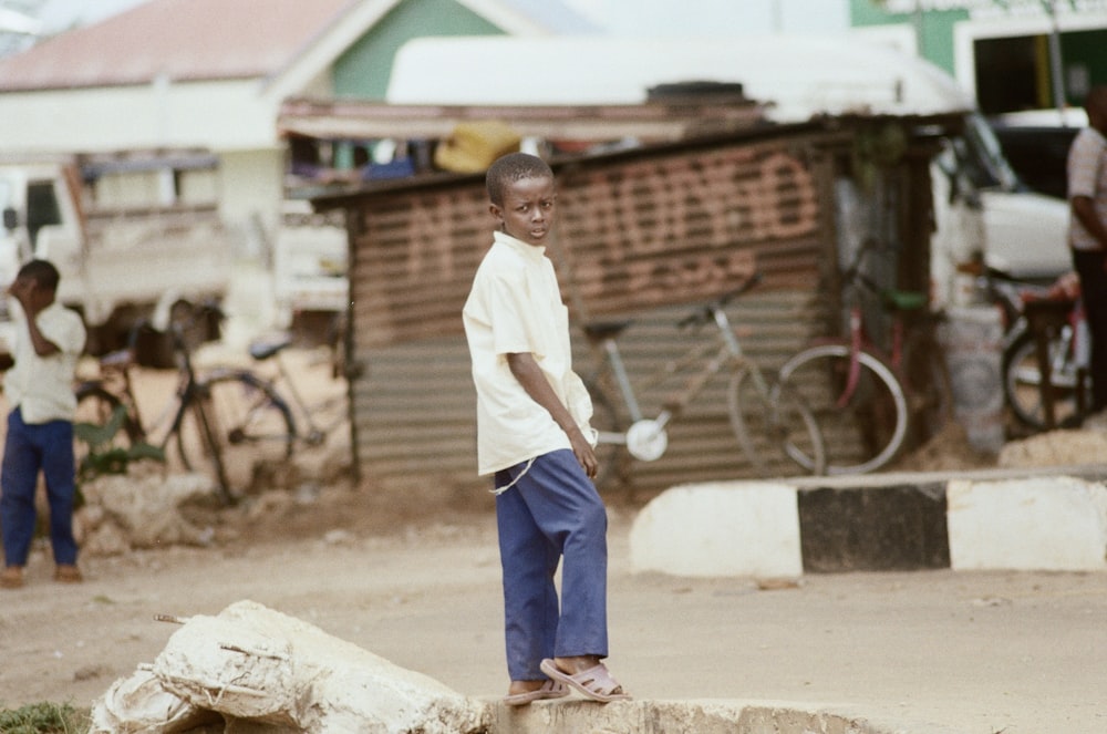 man in white button up shirt and blue denim jeans standing on brown concrete pavement during