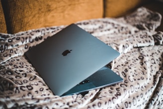 silver macbook on white and brown textile