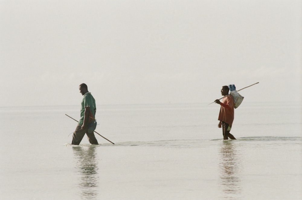 man and woman holding hands while walking on the beach during daytime