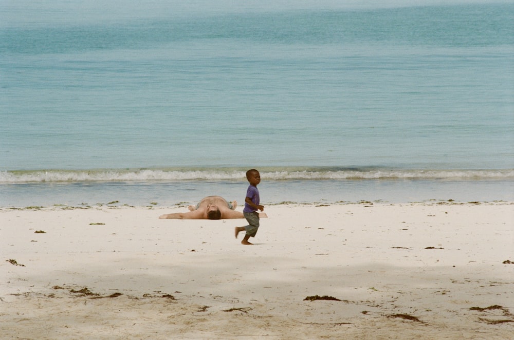 man in black shorts carrying girl in black and white shirt on beach during daytime