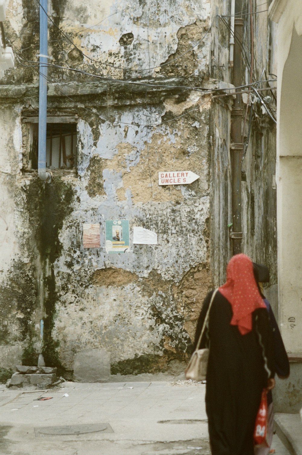 woman in red hijab standing in front of white wooden door