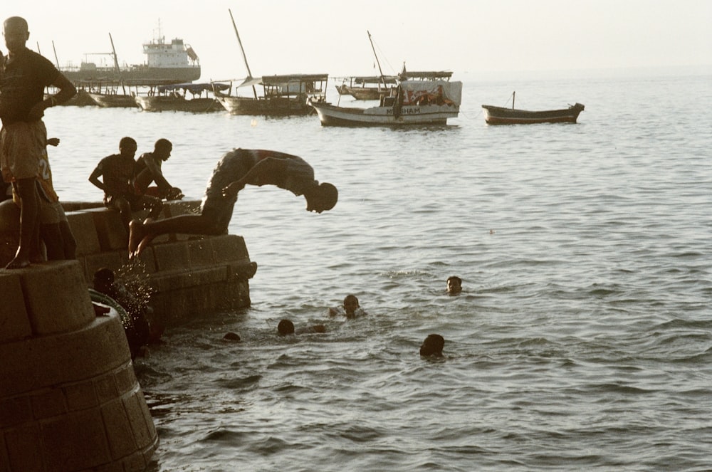 man in black jacket sitting on brown concrete dock during daytime