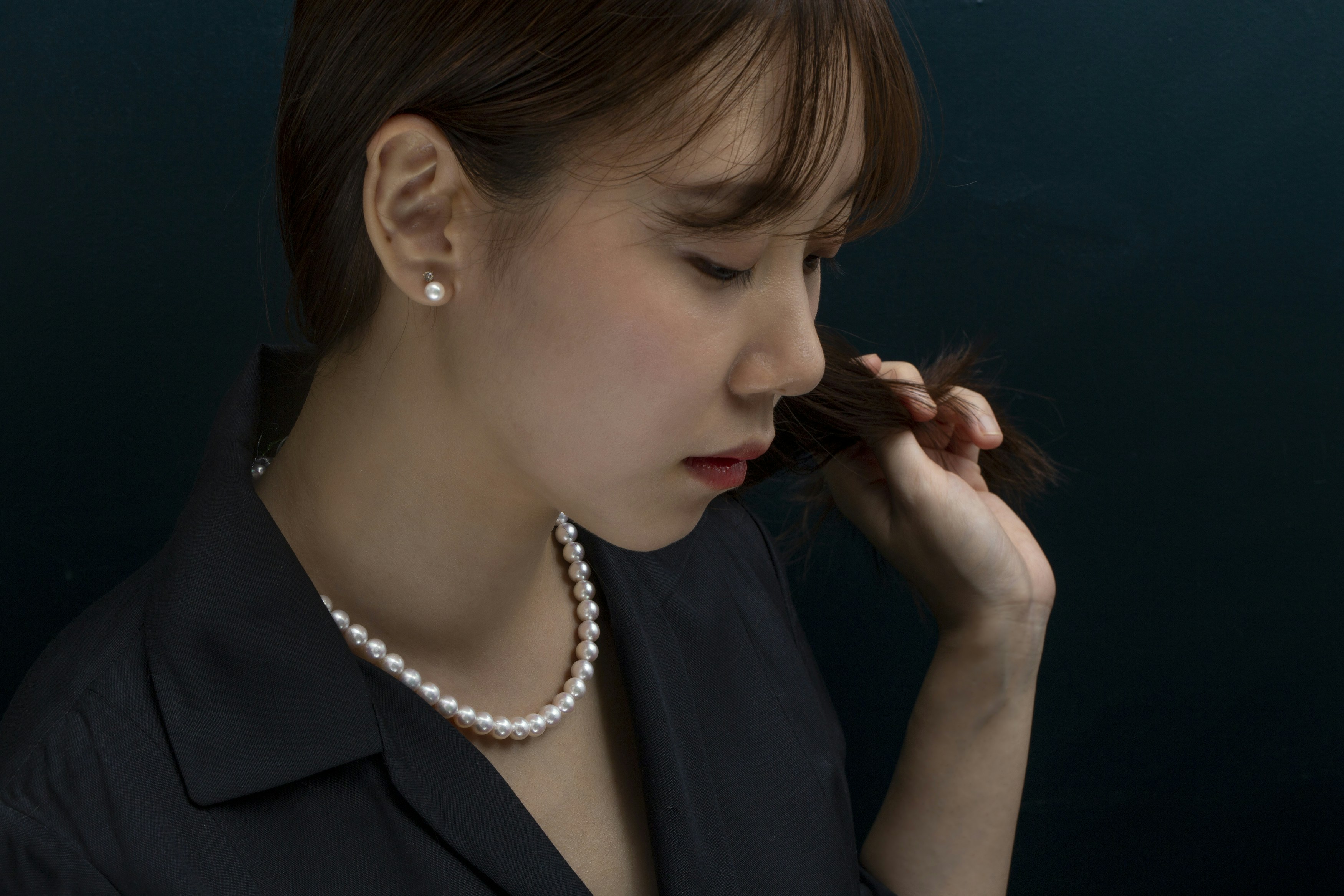 woman in black blazer wearing white pearl necklace