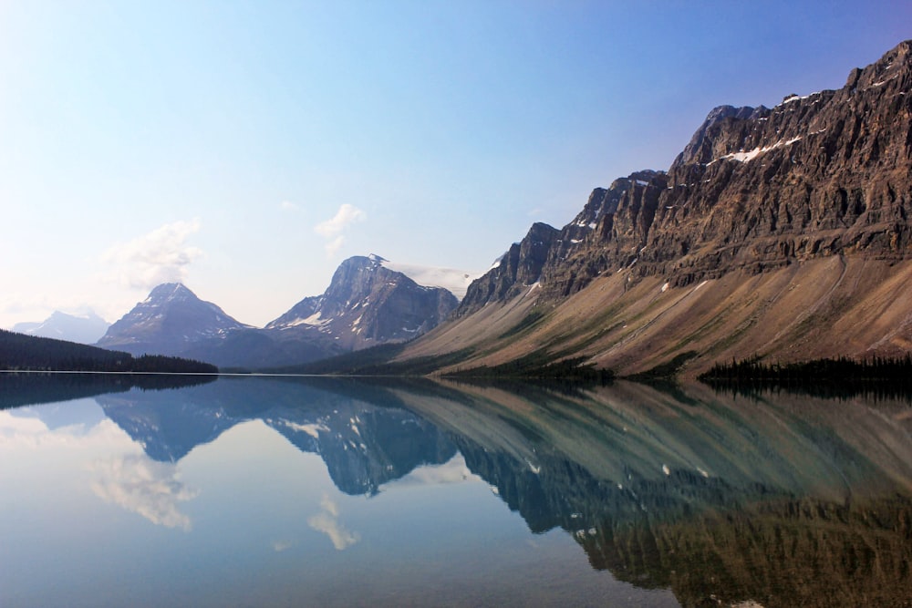 brown and white mountains beside lake under blue sky during daytime