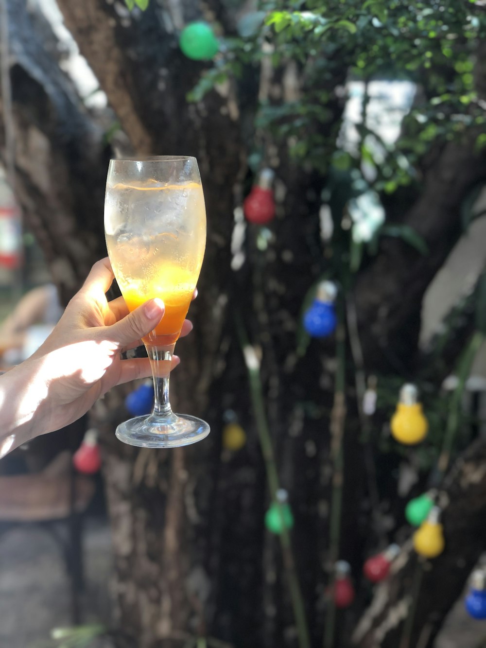 person holding clear wine glass with yellow liquid