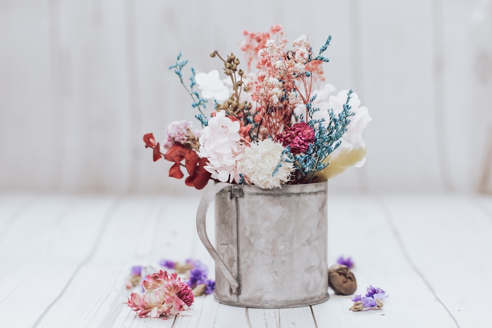 white pink and yellow flowers in gray steel watering can