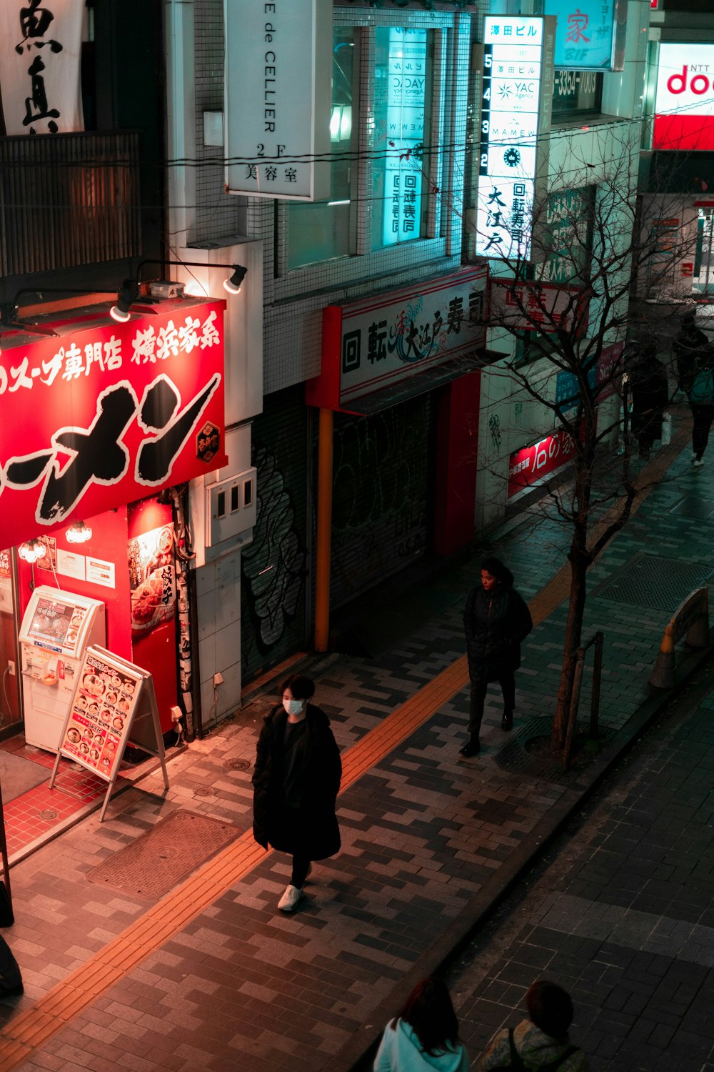 woman in black coat standing near red and white store signage during daytime