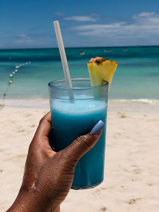 person holding blue liquid in clear drinking glass with white straw in Trelawny Jamaica