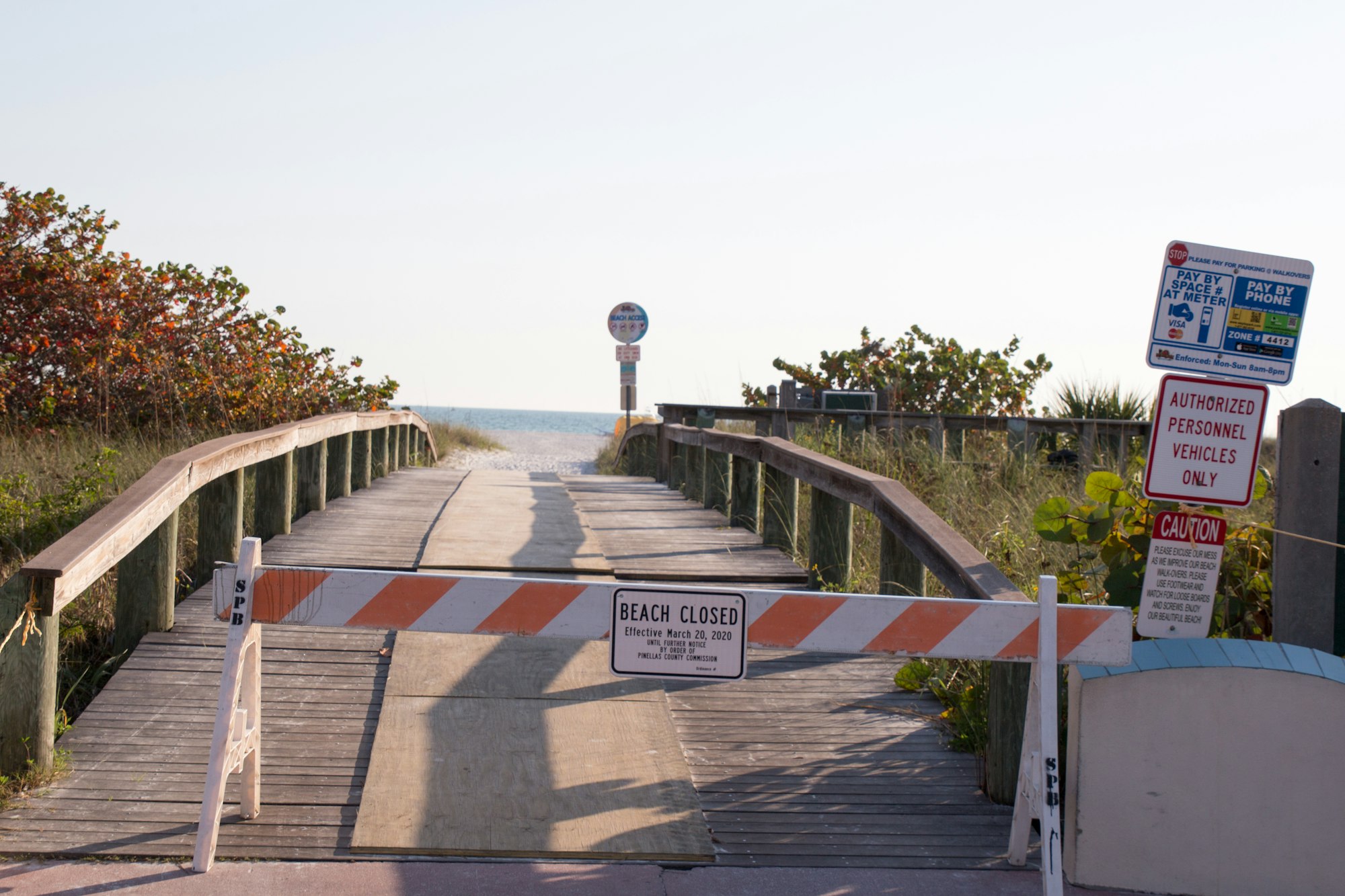 Photo of a path to an ocean beach with a temporary barrier that says "beach closed"