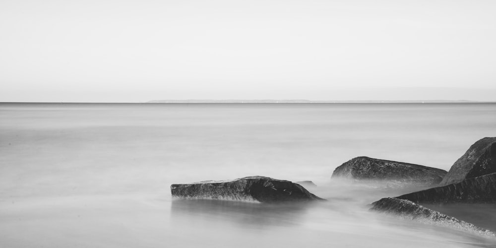 grayscale photo of rock formation on sea