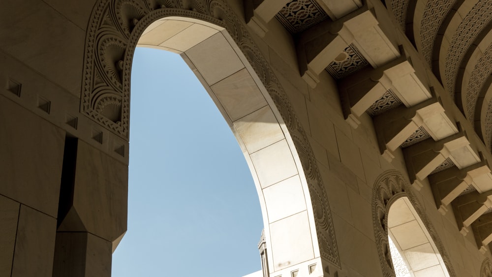 low angle photography of beige concrete building under blue sky during daytime