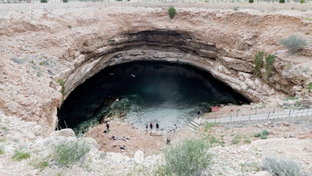 people in body of water in cave during daytime