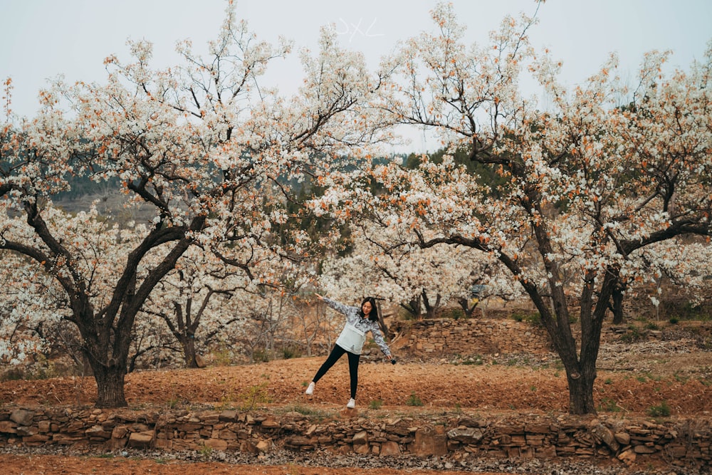 woman in white long sleeve shirt and blue denim jeans standing on brown field with brown