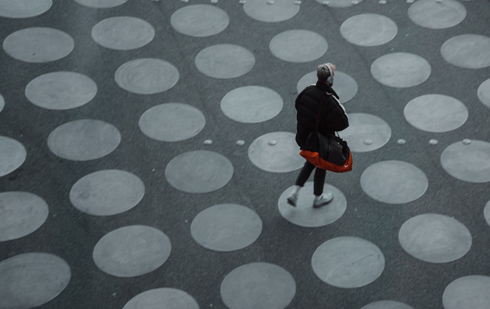 man in black jacket and black pants walking on gray and white polka dot floor