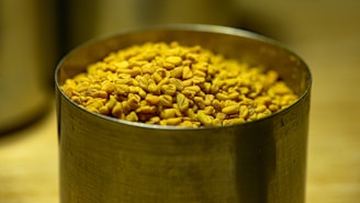 Golden fennel seeds displayed in a traditional Indian brass container.