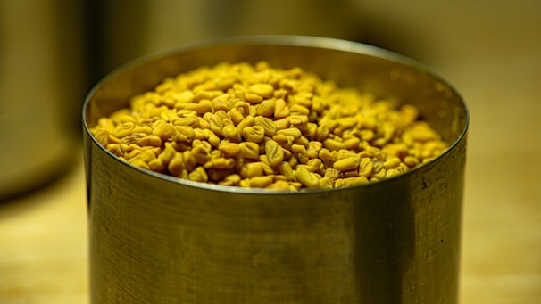 Golden fennel seeds displayed in a traditional Indian brass container.