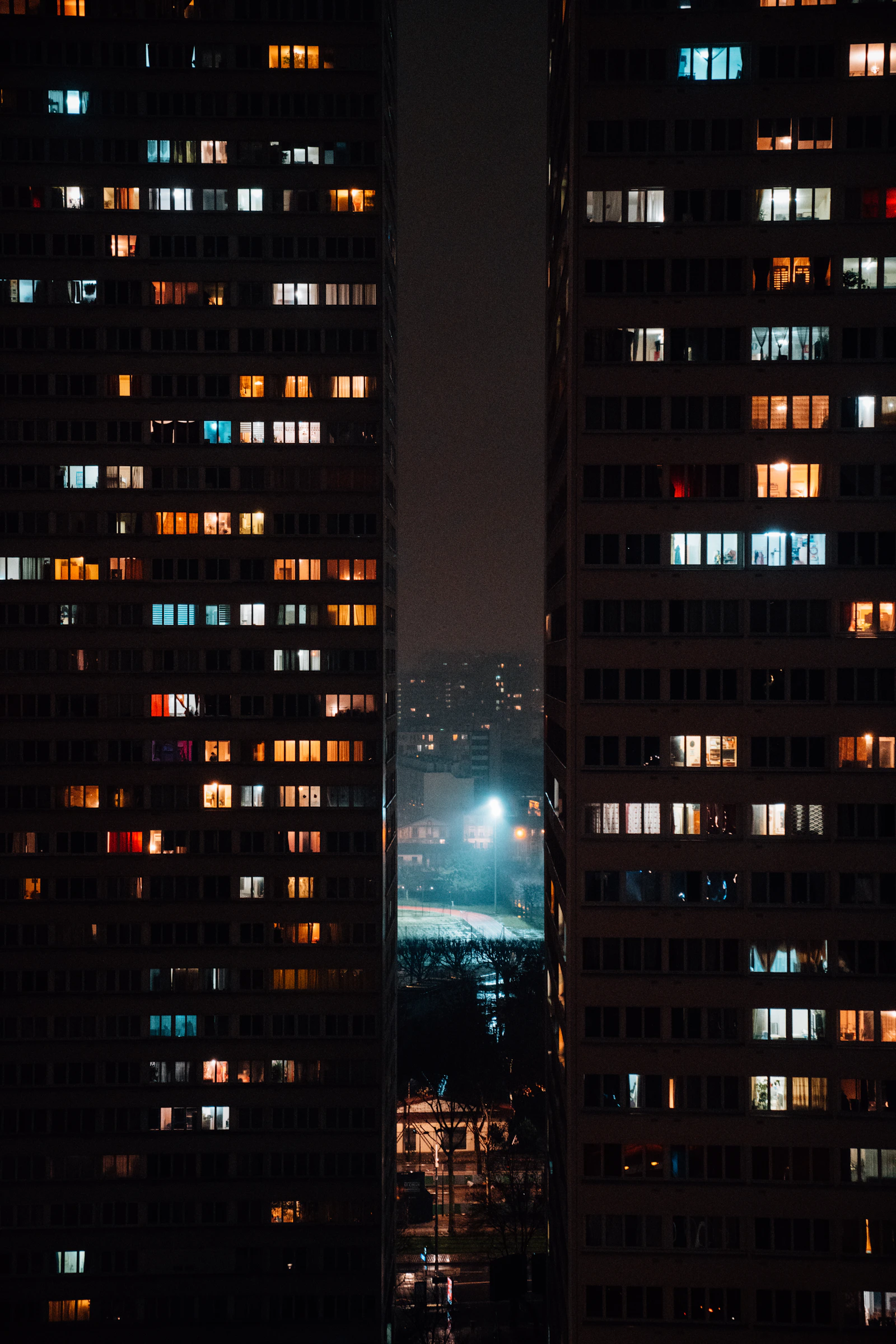 Illuminated windows in a residential building at night reveal different patterns of use.